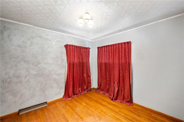 spare room with wood finished floors, visible vents, and ornamental molding