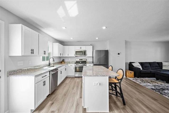 167 Alta Vista Dr, Imperial, PA 15126 - kitchen featuring white cabinets, stainless steel appliances, light wood-type flooring, open floor plan, and a kitchen bar