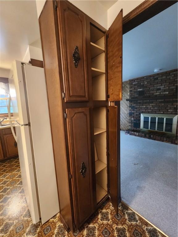room details with open shelves, dark carpet, freestanding refrigerator, and a fireplace