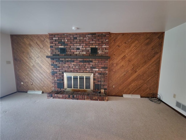 unfurnished living room featuring wood walls, carpet flooring, a fireplace, baseboards, and visible vents