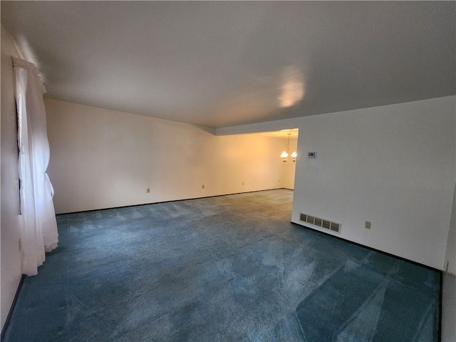 empty room featuring a notable chandelier, visible vents, and carpet