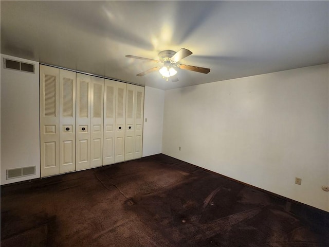 unfurnished bedroom featuring visible vents, dark carpet, ceiling fan, and a closet