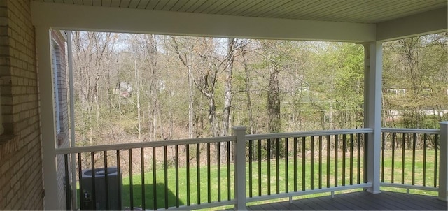 deck with a forest view, cooling unit, and a yard
