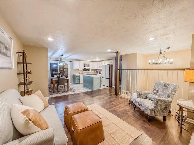 living area featuring recessed lighting, an inviting chandelier, and hardwood / wood-style flooring