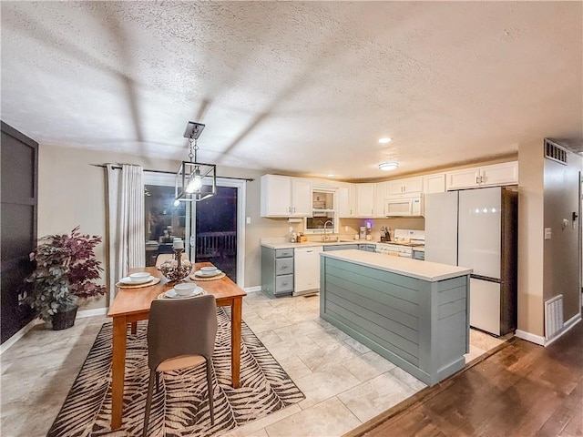 kitchen with white appliances, light countertops, white cabinets, baseboards, and visible vents