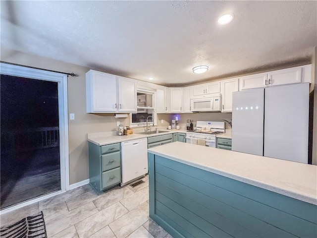 kitchen with white cabinets, a sink, light countertops, baseboards, and white appliances