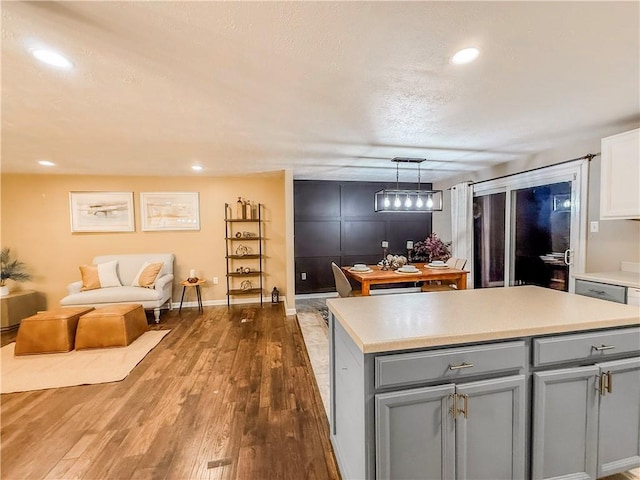 kitchen with a center island, gray cabinetry, wood finished floors, and light countertops
