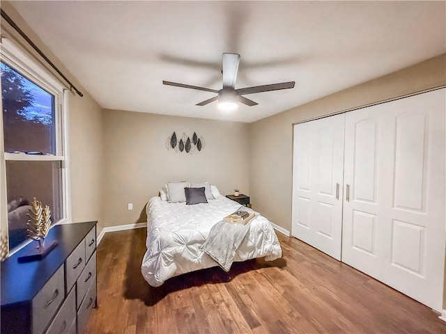 bedroom featuring wood finished floors, a closet, a ceiling fan, and baseboards