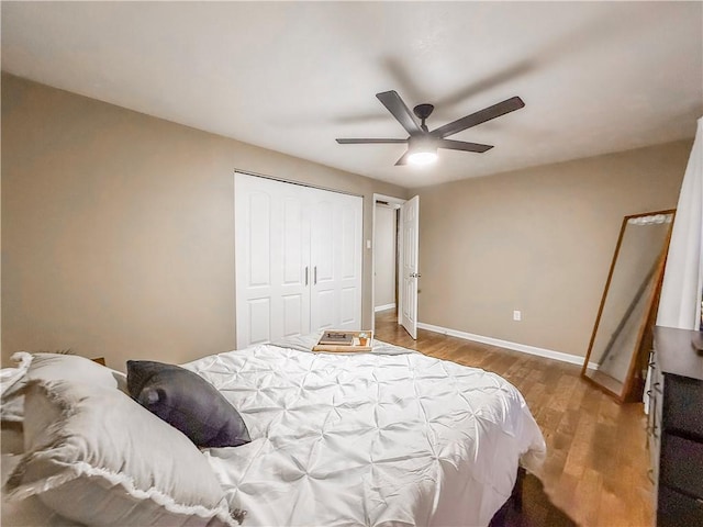 bedroom with wood finished floors, ceiling fan, a closet, and baseboards