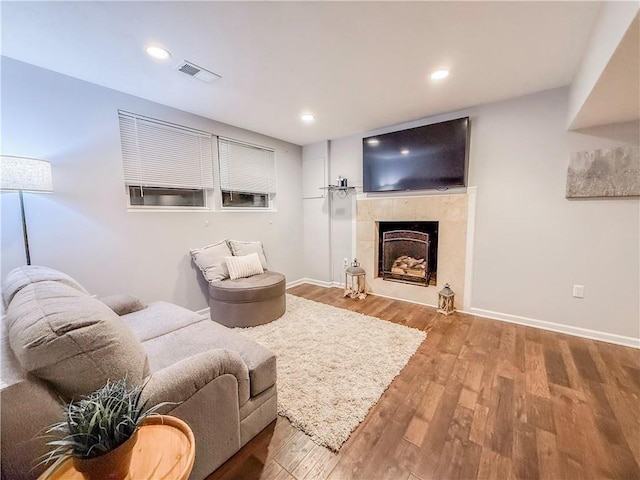 living area with visible vents, baseboards, recessed lighting, wood finished floors, and a tiled fireplace