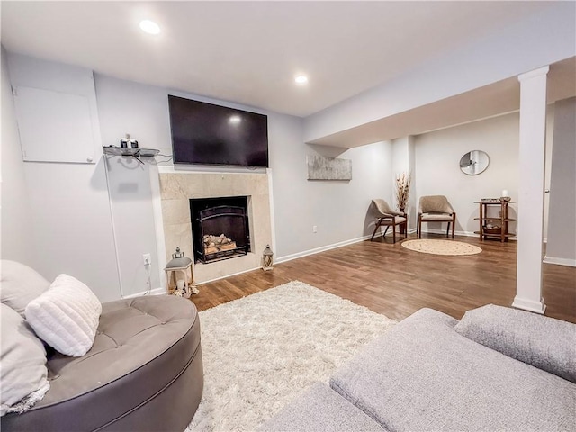 living area with recessed lighting, a tile fireplace, decorative columns, baseboards, and wood finished floors