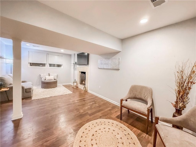 interior space featuring visible vents, baseboards, recessed lighting, a fireplace, and wood finished floors