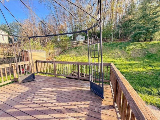 deck featuring a lawn, fence, a shed, and an outbuilding