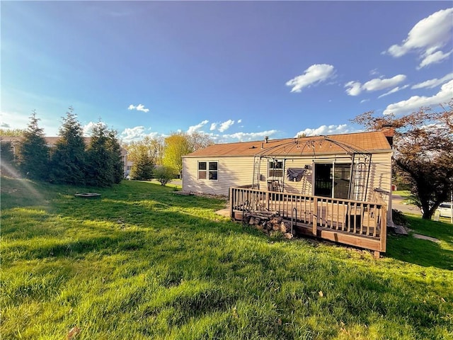 rear view of house featuring a deck and a yard