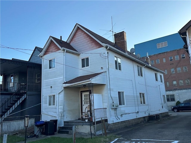 rear view of house with cooling unit and a chimney