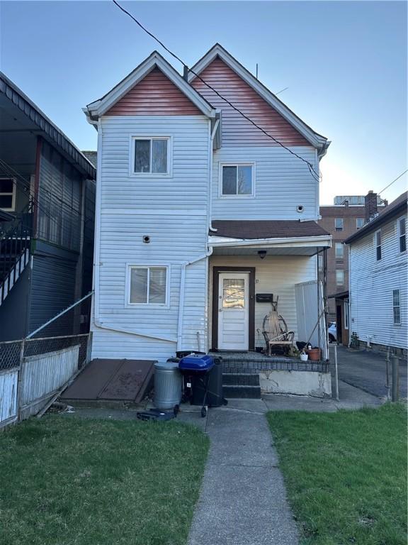 rear view of property with a lawn and fence