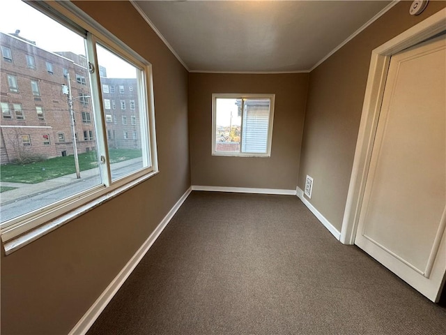 unfurnished room with crown molding, dark colored carpet, and baseboards