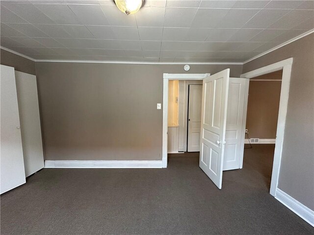 unfurnished bedroom featuring dark colored carpet, crown molding, and baseboards