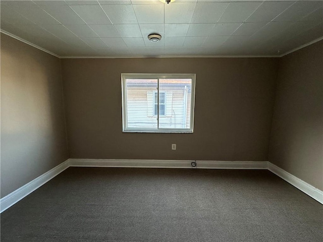 unfurnished room with baseboards, dark carpet, and crown molding
