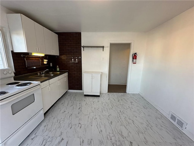 kitchen with tasteful backsplash, white cabinets, a sink, visible vents, and white range with electric cooktop