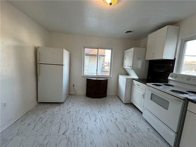 kitchen with stacked washer / dryer, white cabinets, baseboards, white appliances, and marble finish floor