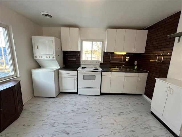 kitchen featuring stacked washer and dryer, white electric stove, marble finish floor, a sink, and visible vents