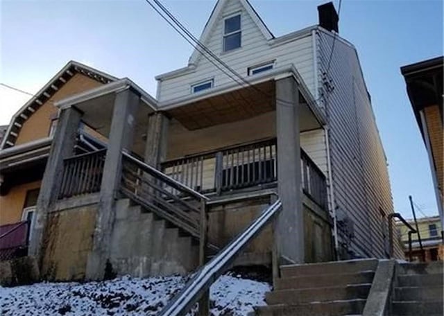 snow covered property featuring stairway and a chimney