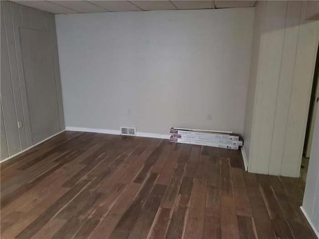 unfurnished room featuring a paneled ceiling, visible vents, wood finished floors, and baseboards