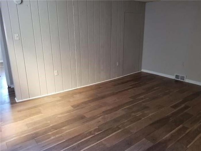 empty room featuring visible vents, baseboards, and wood-type flooring