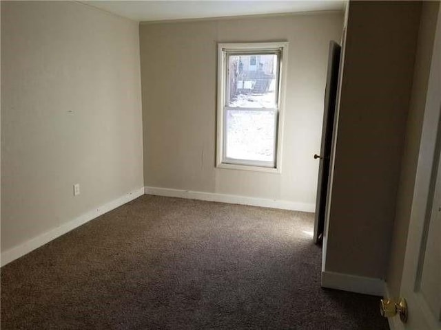 empty room with baseboards, dark colored carpet, and a healthy amount of sunlight