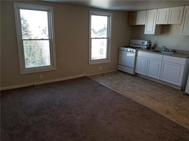 kitchen with gas range gas stove, light carpet, white cabinetry, and a sink