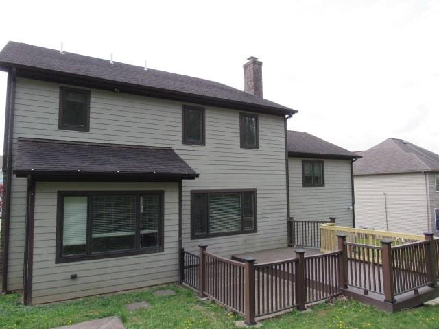 back of property with a chimney and a wooden deck