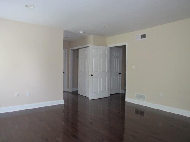 spare room featuring visible vents, dark wood finished floors, and baseboards