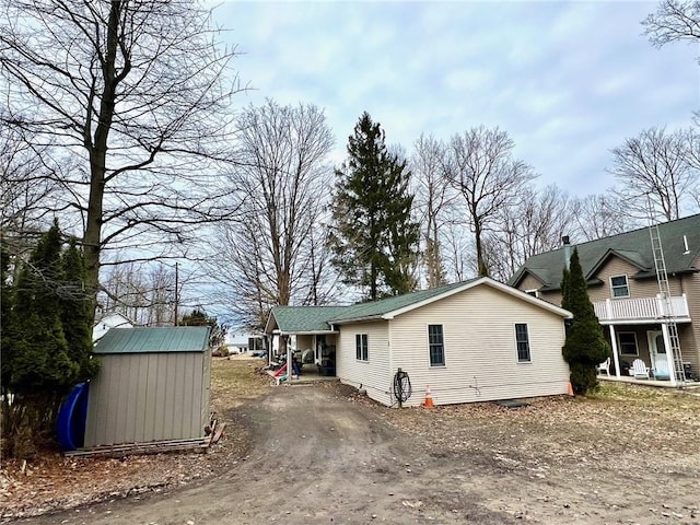 view of property exterior with an outbuilding, a storage shed, dirt driveway, and a porch