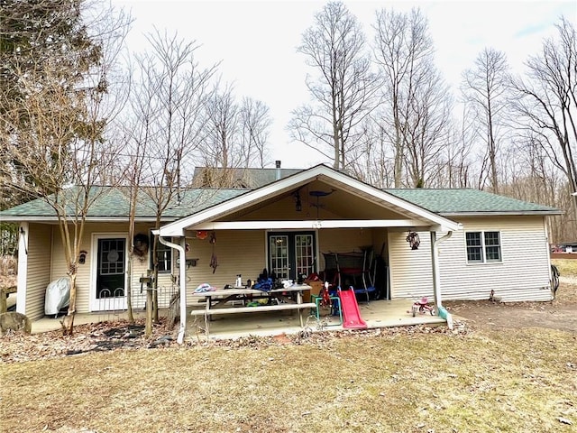 rear view of property with a shingled roof, french doors, and a patio area