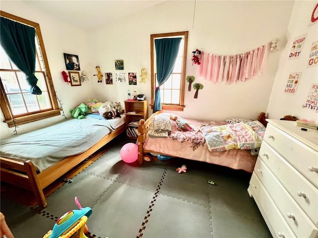 bedroom featuring concrete floors, multiple windows, and lofted ceiling