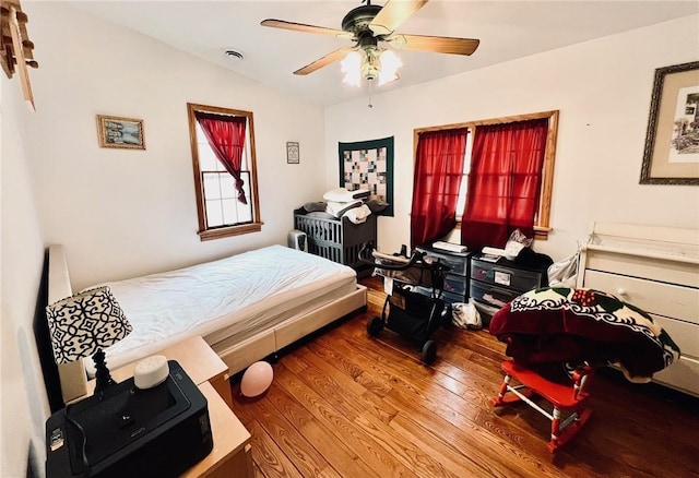 bedroom featuring lofted ceiling, wood finished floors, a ceiling fan, and visible vents