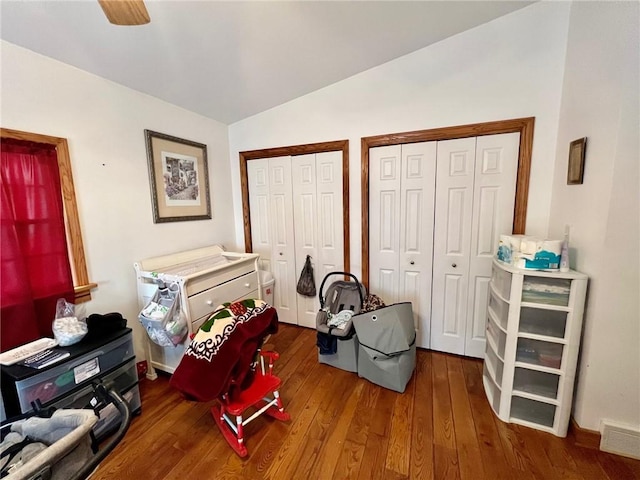 bedroom with hardwood / wood-style floors, vaulted ceiling, multiple closets, and visible vents