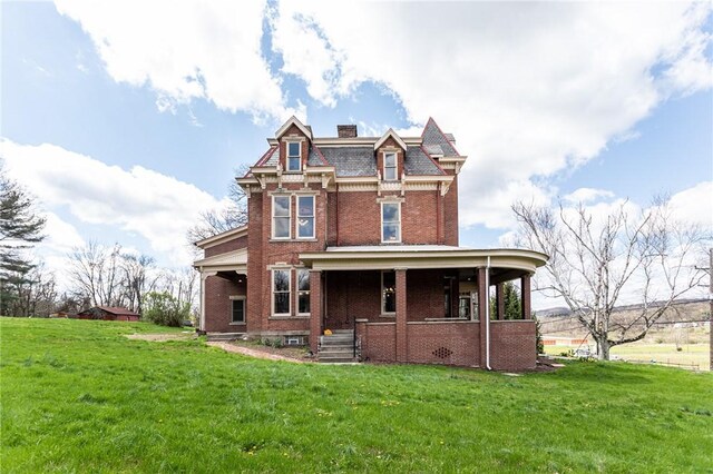 view of front facade featuring a front yard, a chimney, a porch, and brick siding