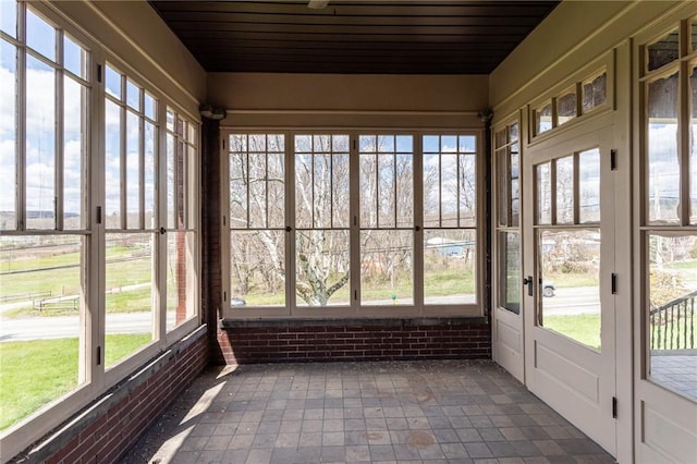 unfurnished sunroom with wooden ceiling, french doors, and brick wall