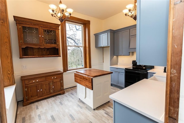 kitchen featuring an inviting chandelier, pendant lighting, light wood-style floors, and black / electric stove