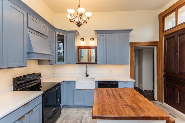 kitchen featuring custom range hood, a sink, wooden counters, black appliances, and an inviting chandelier