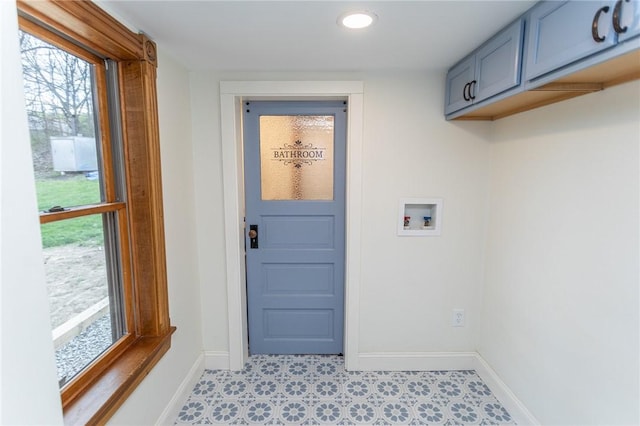 clothes washing area featuring baseboards, hookup for a washing machine, a healthy amount of sunlight, and cabinet space