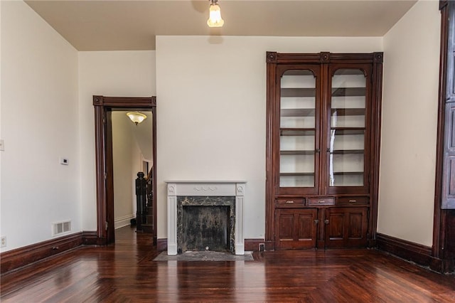 unfurnished living room featuring baseboards, visible vents, parquet flooring, and a fireplace