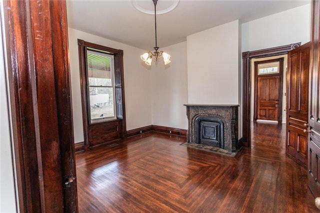 unfurnished living room with a fireplace with flush hearth, wood finished floors, a chandelier, and baseboards
