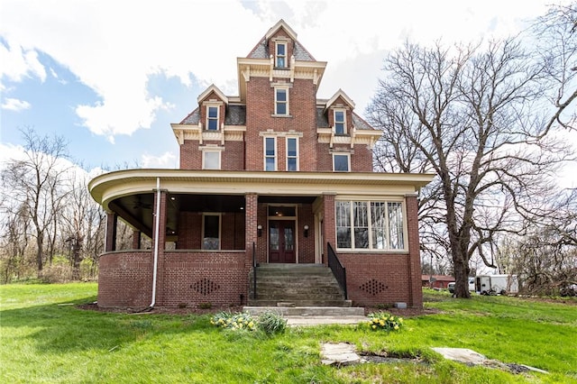 victorian-style house featuring a porch, a front yard, and brick siding