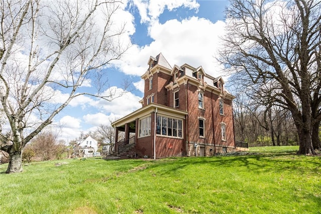 view of side of property featuring a yard, mansard roof, and brick siding