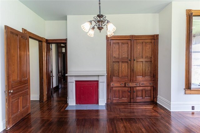 interior space featuring a notable chandelier, a fireplace with flush hearth, wood finished floors, and baseboards