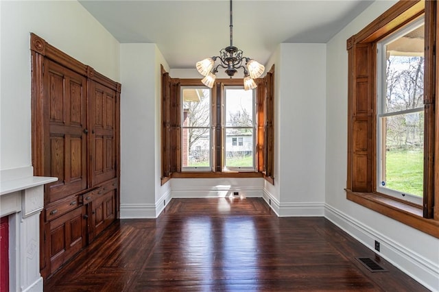 unfurnished dining area featuring visible vents, a notable chandelier, dark wood-style flooring, and baseboards