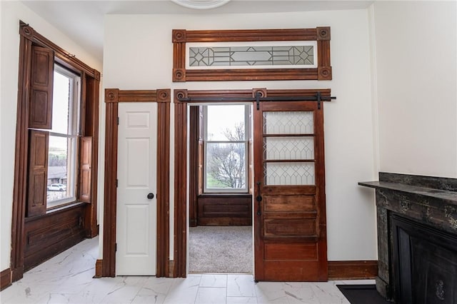 interior space featuring a healthy amount of sunlight, baseboards, marble finish floor, and a premium fireplace